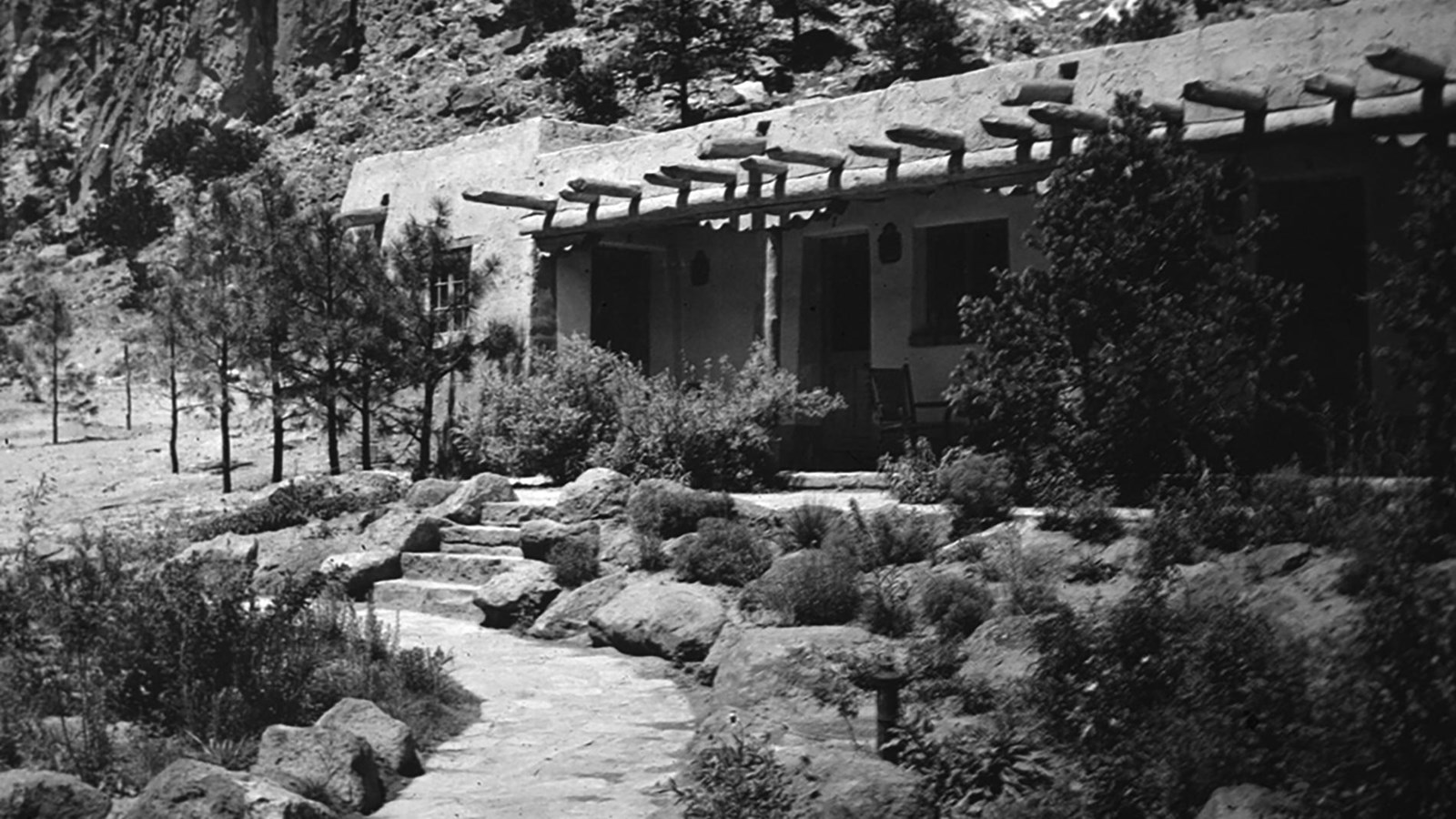 a stone building with protruding wooden beams, a stone sidewalk and stairs