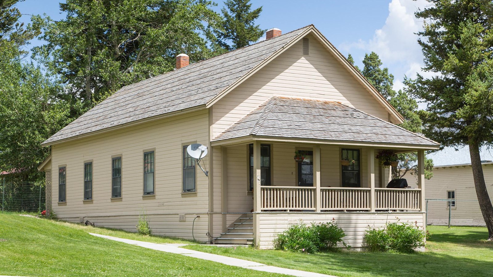 A historic building with off-white siding, a wooden, shingled roof, and a small porch.