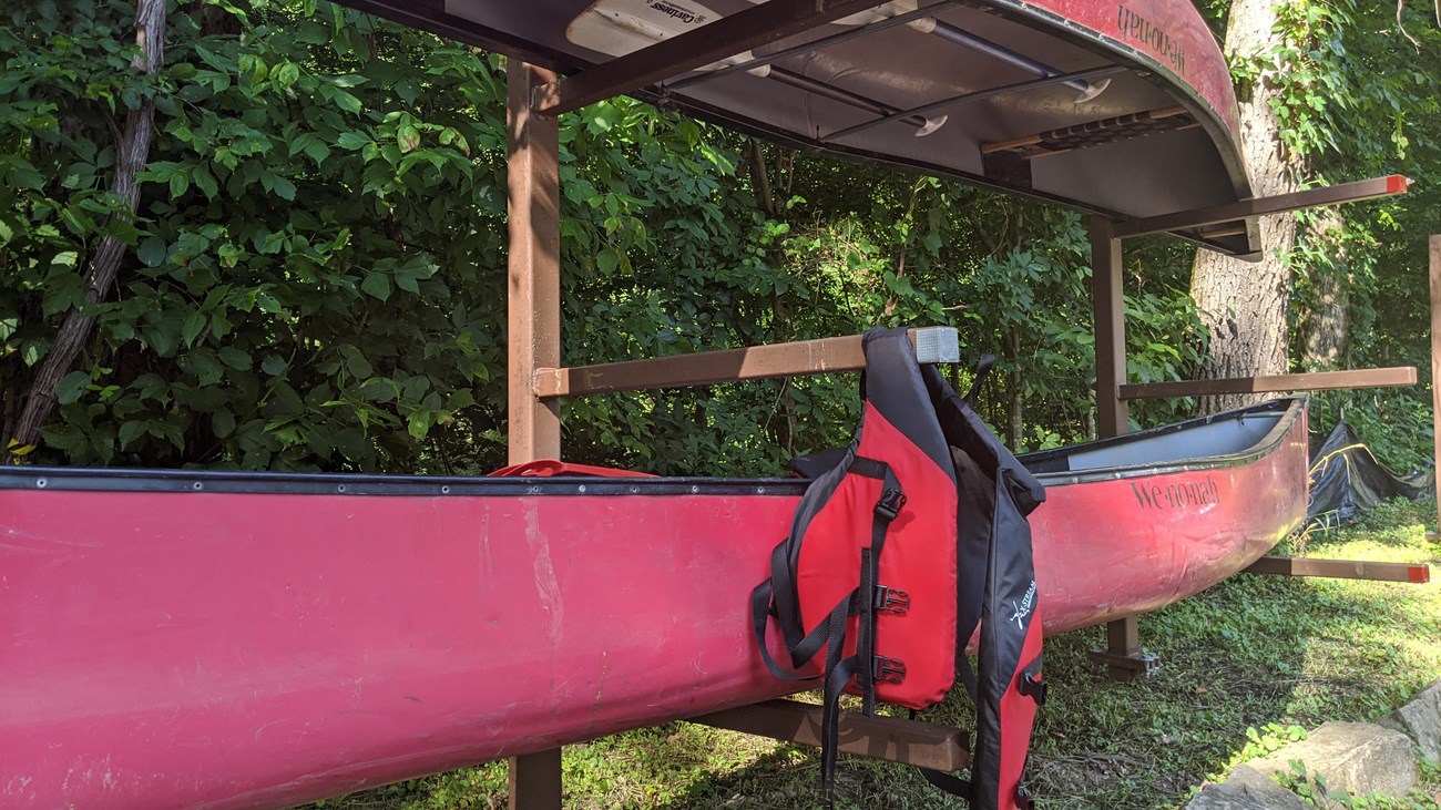 Two canoes sitting on a rack with a PDF hanging.