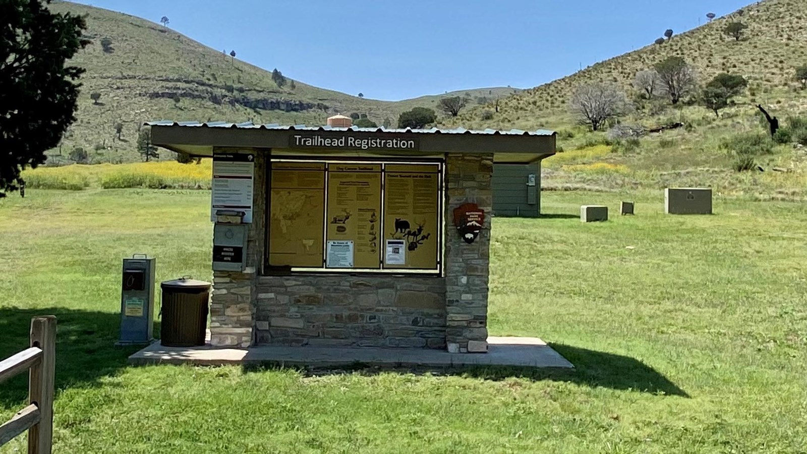 Stone kiosk with trail information at the head of a meadow area