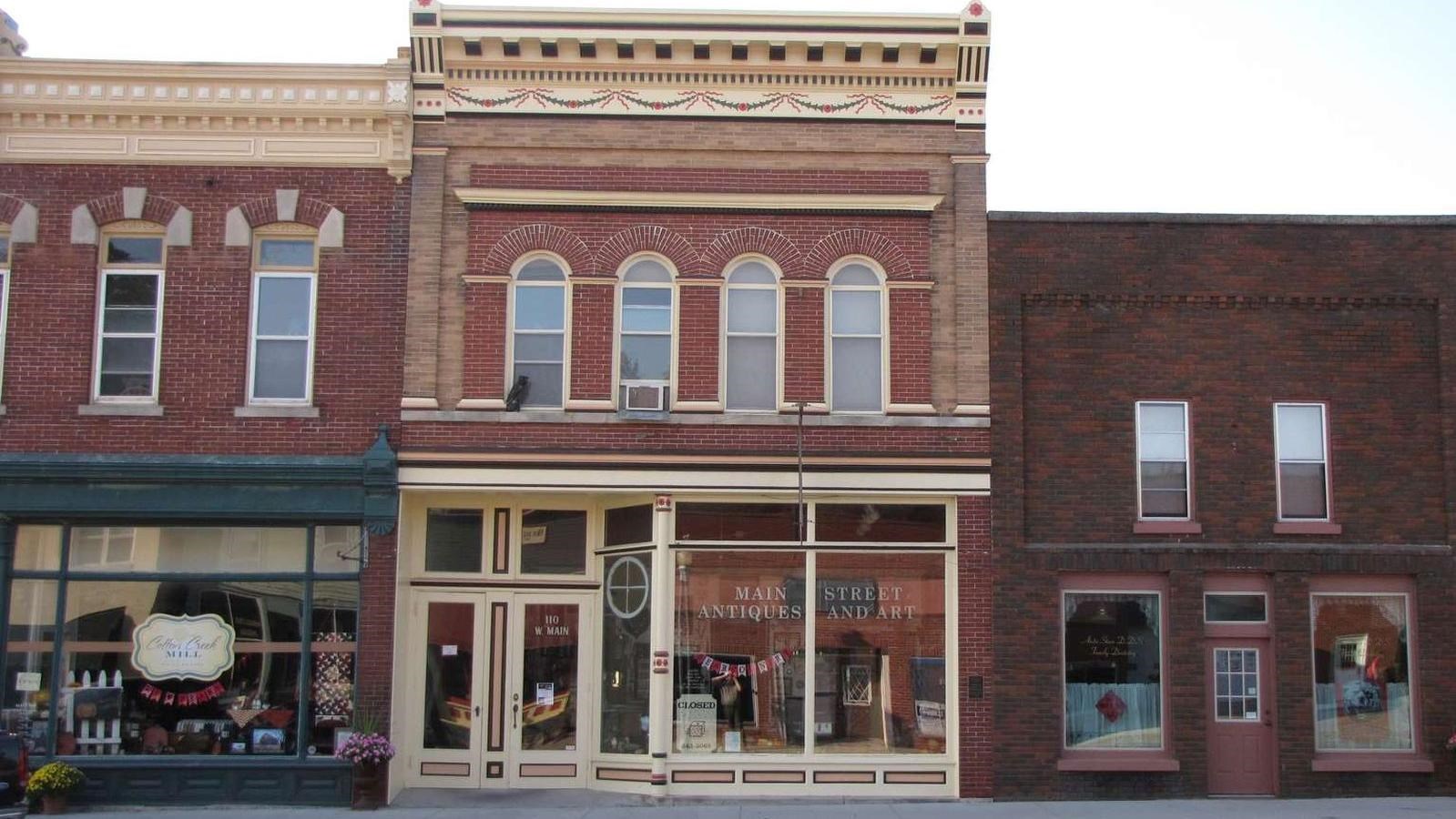 An old downtown building is brick with cream trim and ornamentation, and arched upstairs windows.