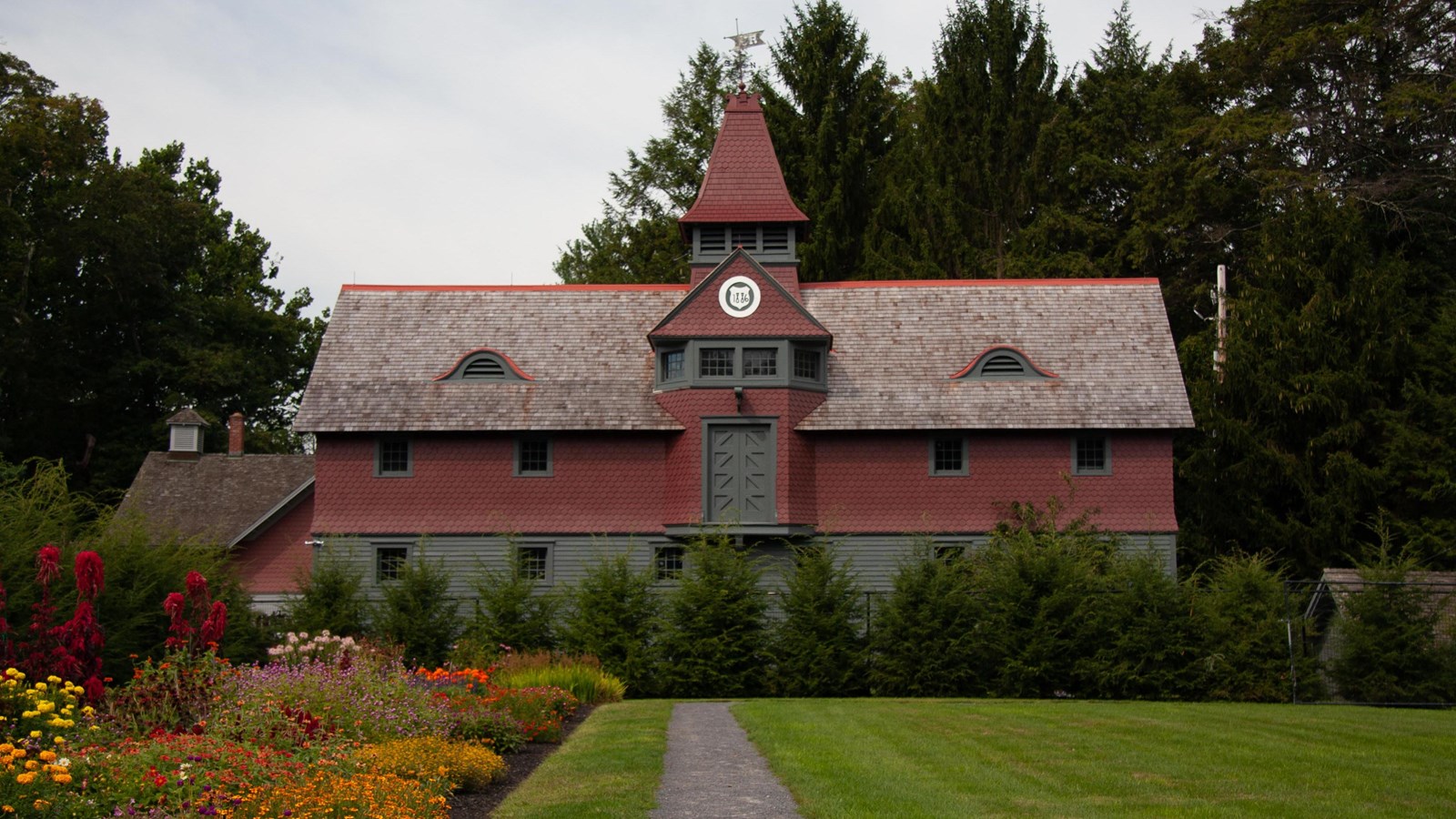 A wood clapboard and shingle building with cupola.