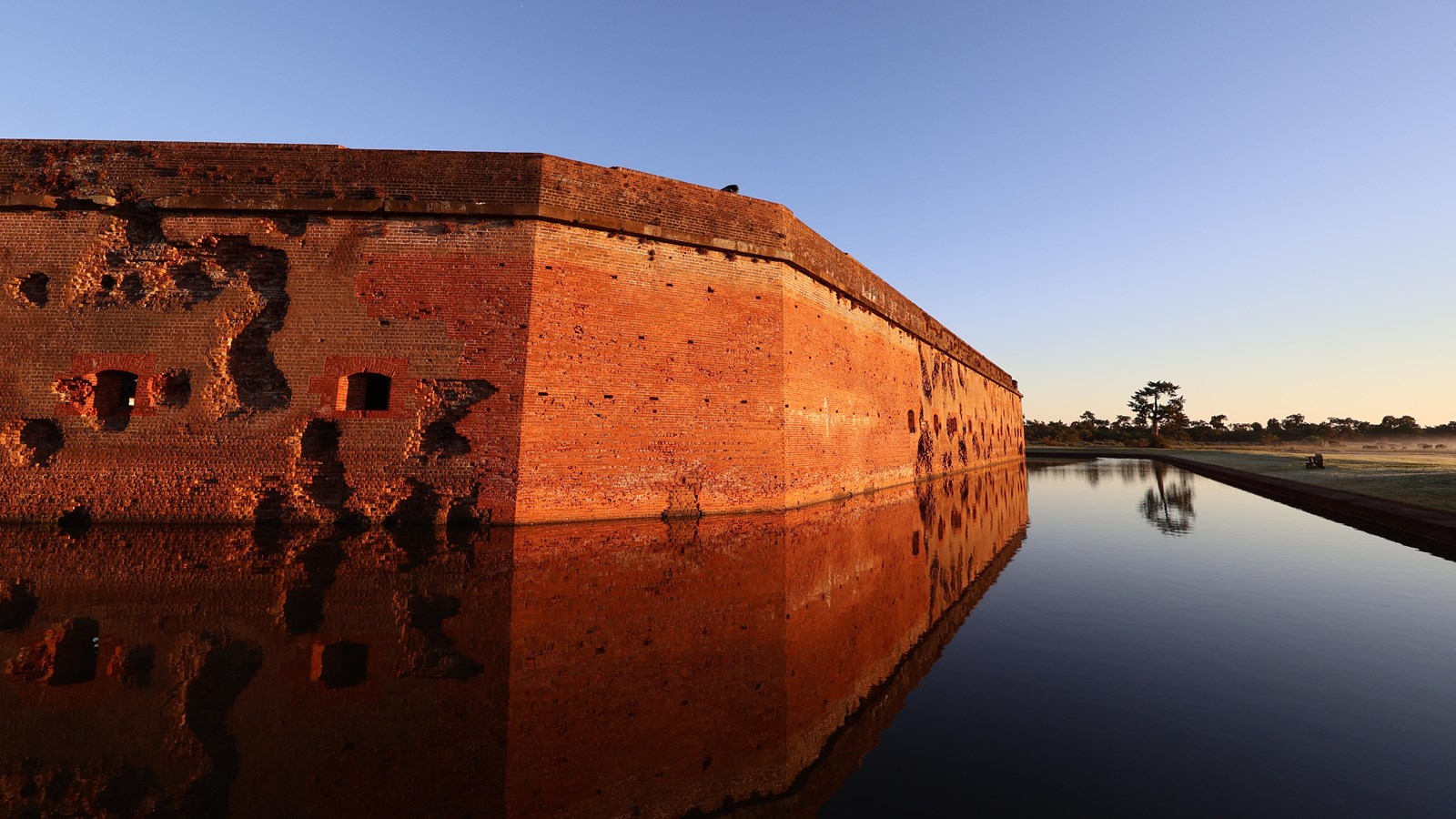A brick fort reflected in a moat.