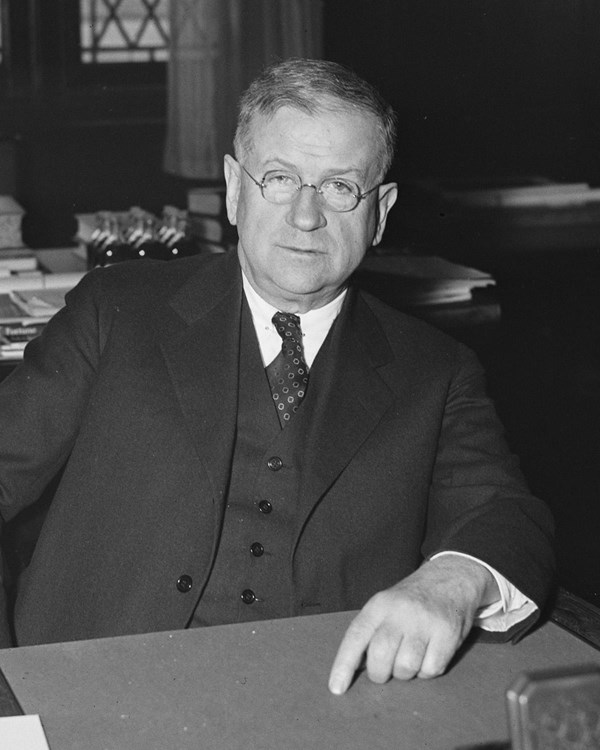 A man in a suit seated behind a desk.