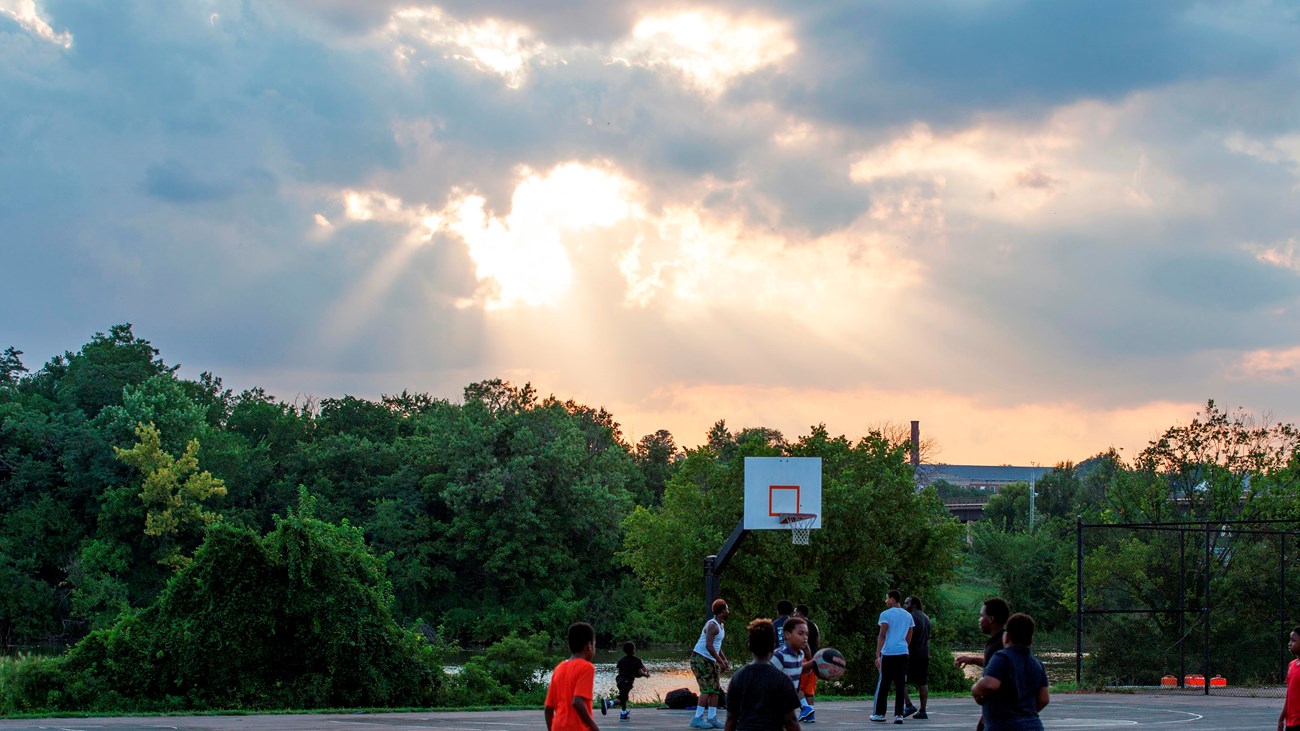 Several people play basektball at sunset in Anacostia Park