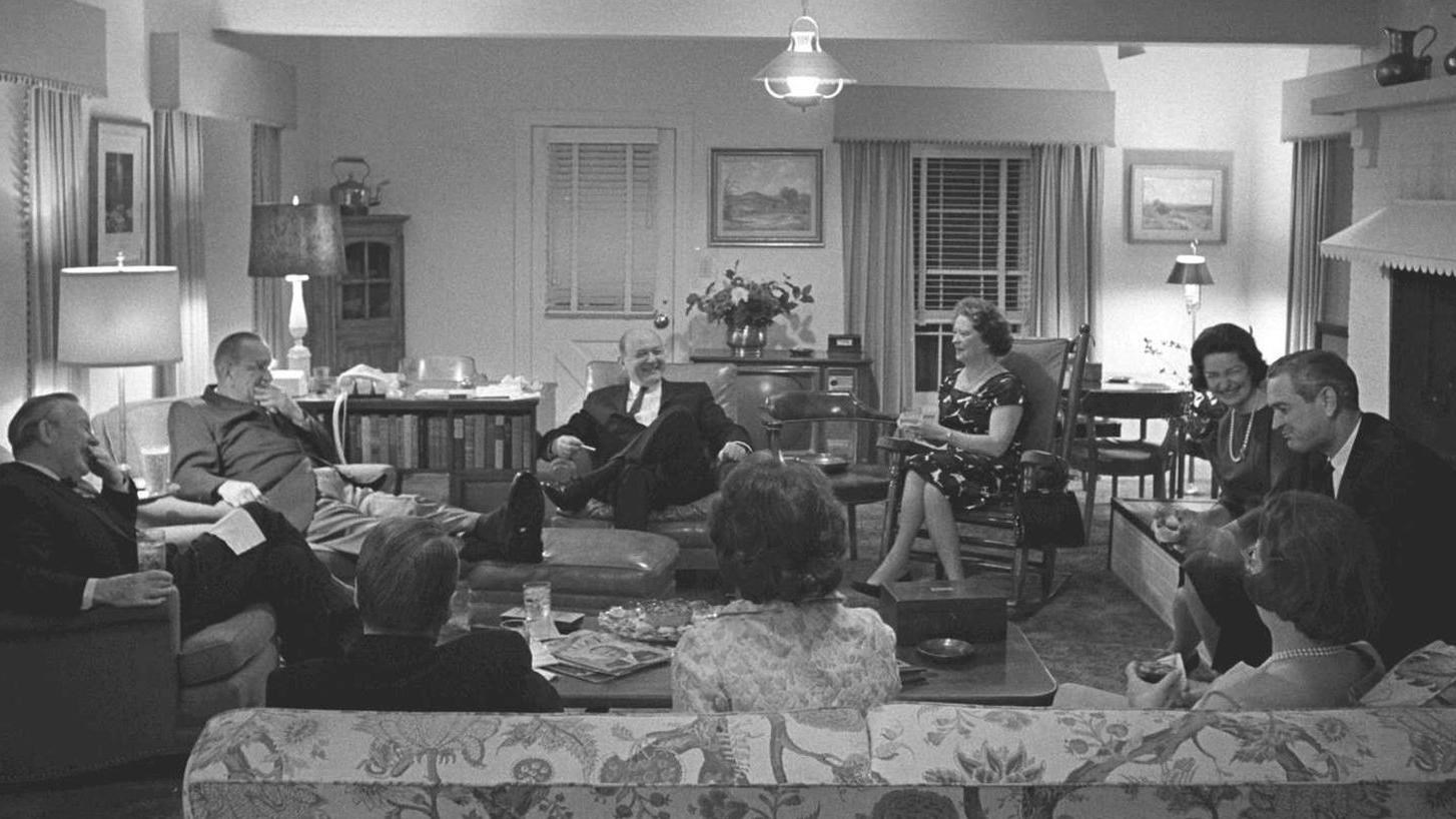 Well-dressed people including the president and first lady enjoy an evening visit in the living room