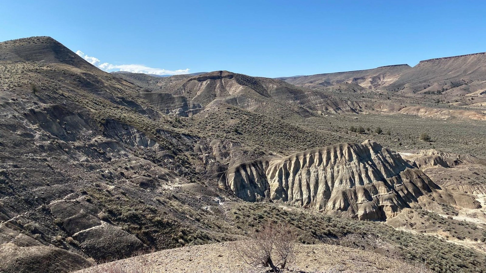 Tan volcanic formation viewed from above that sits in a valley with shrubs and plateaus