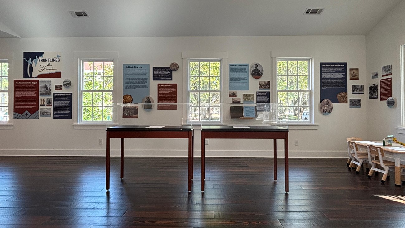A room with several windows, and red, white, and blue exhibit panels on the walls.