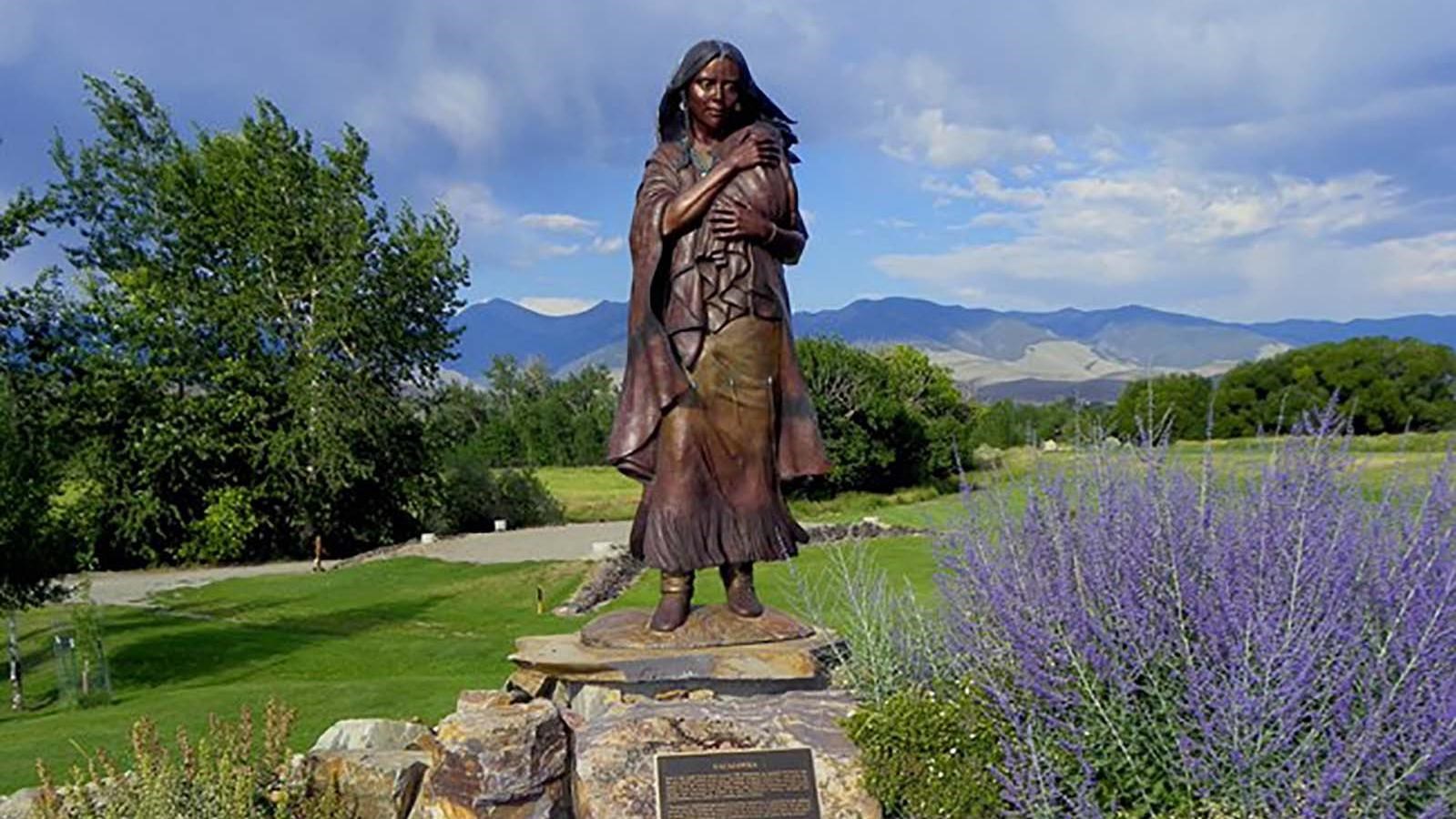 Statue of women in an open valley with mountains in the background