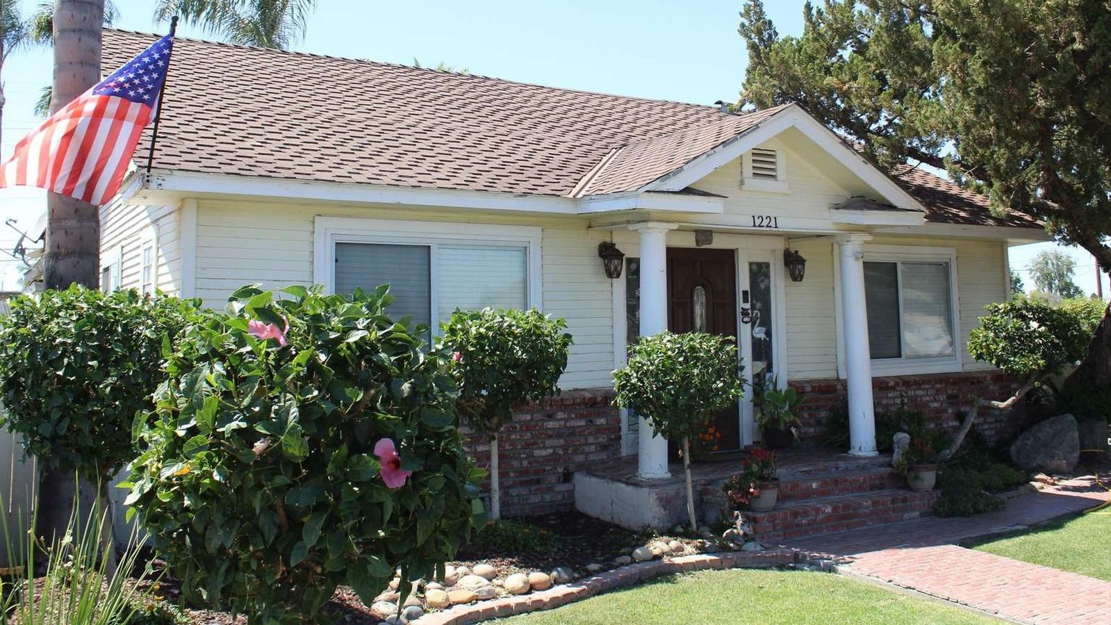 A trim house with careful landscaping and an American flag