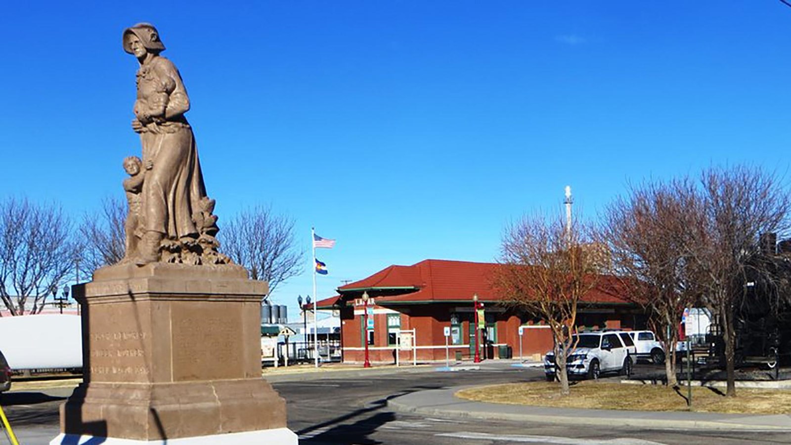 A statue of a woman in front of a one-story building with a red roof.