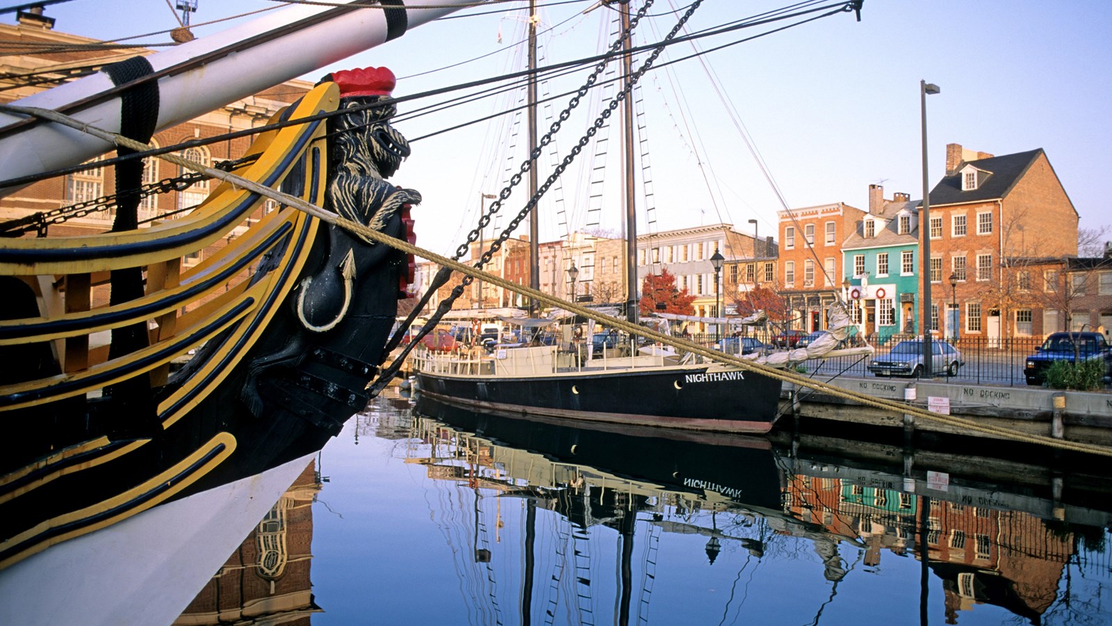 A ship is docked with historic structures in the background; another ship looms in the foreground.