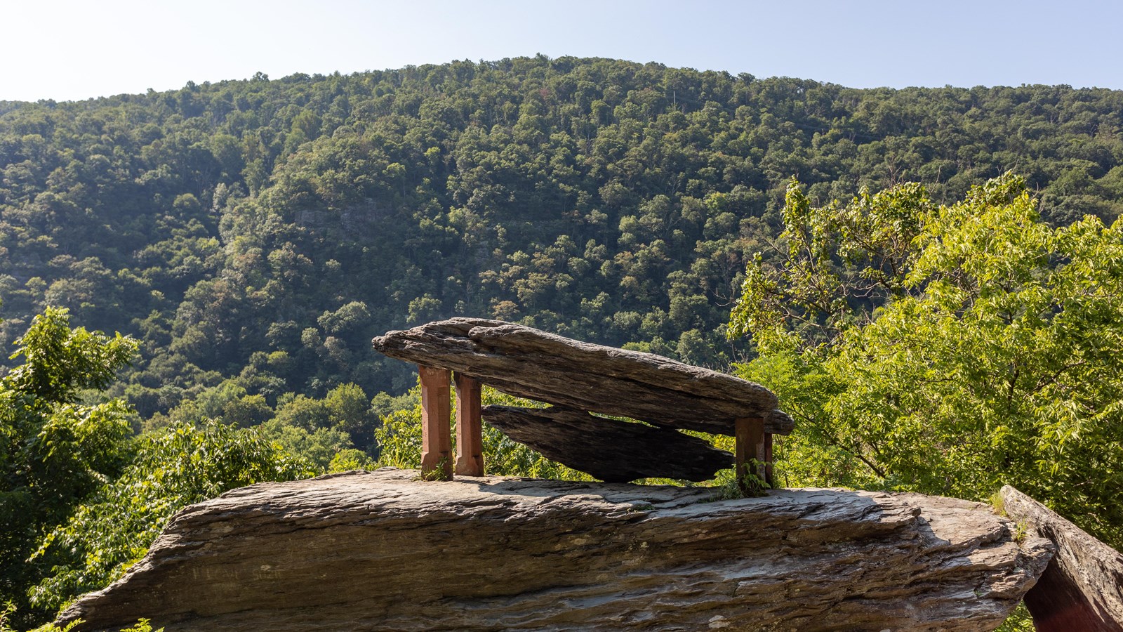 Two rocks rest on top of a larger boulder, supported by concrete columns.