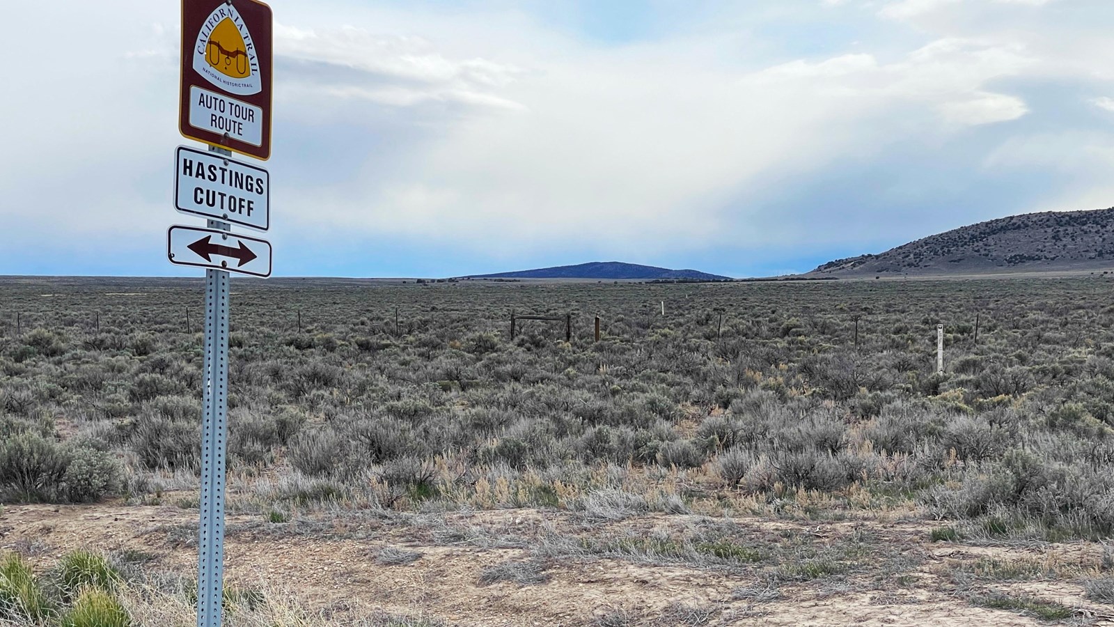 A sign for the California Trail Auto Tour Route in foreground. White posts mark the wagon trace.