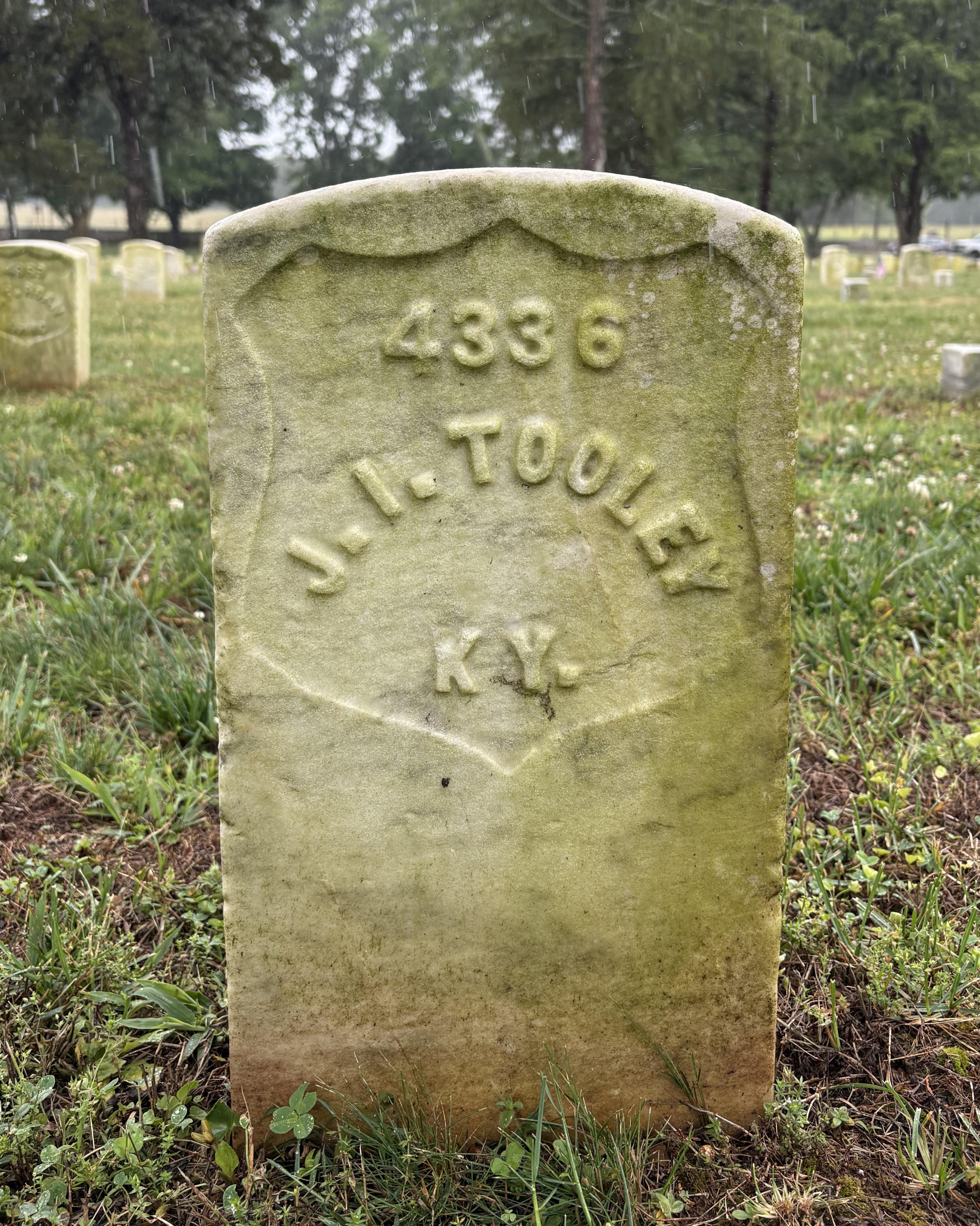 Marble headstone with the name "J. I. Tooley" inscribed on its face. 