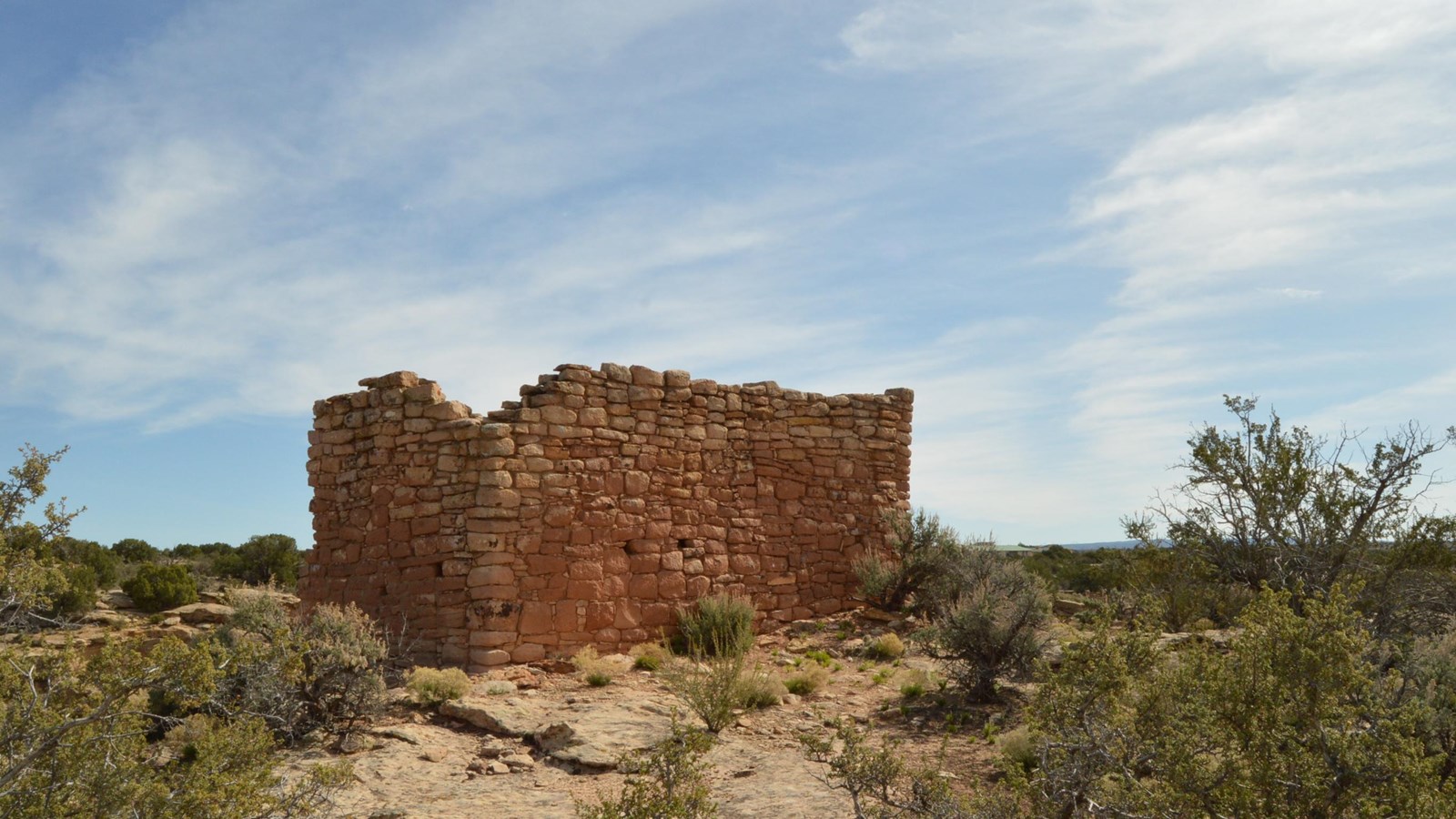 a rectangular stone structure on pale sandstone, blue sky behind