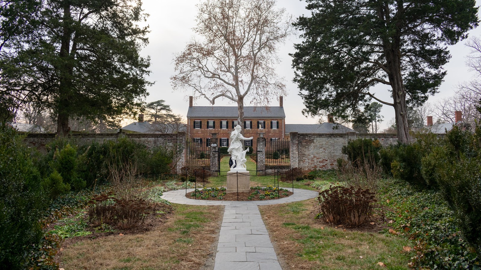 Photograph of a two story brick house with single story wings on either side.