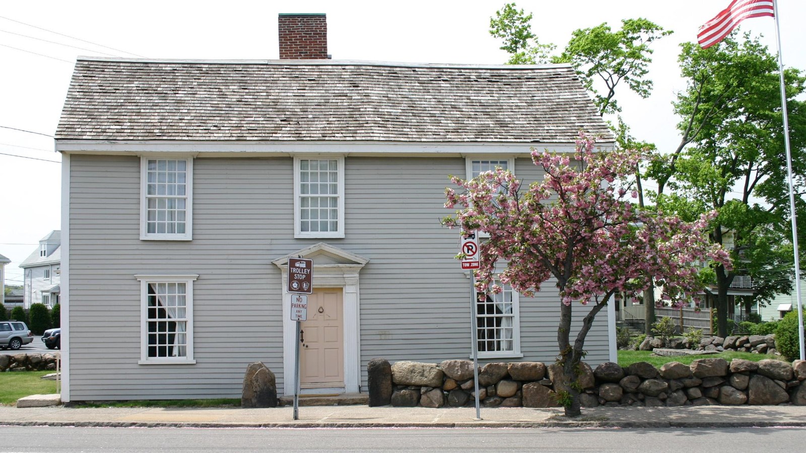 A grey, saltbox style home with a yellow door.
