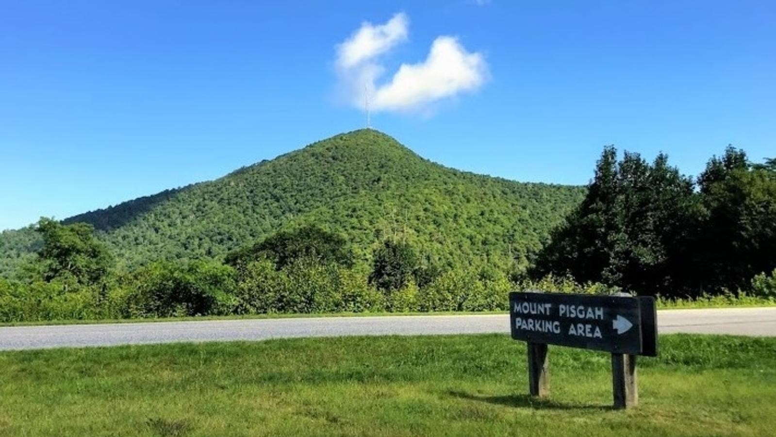 a mountain with a radio tower on top rises behind a sign reading Mount Pisgah Parking Area