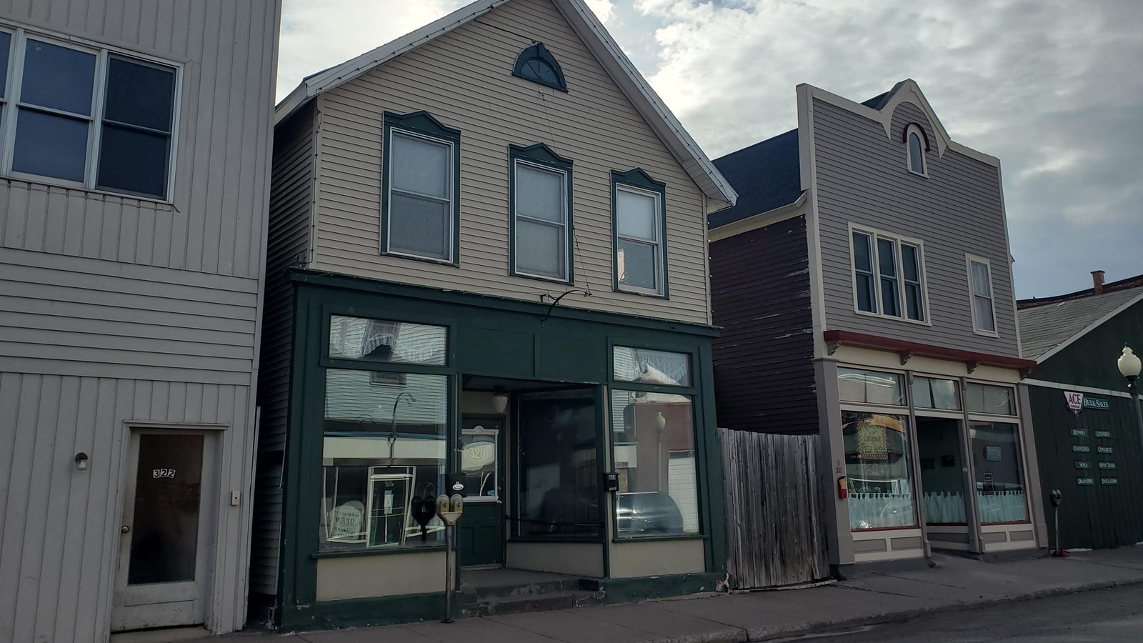Two-story wood-frame building with large storefront windows and green window trim.