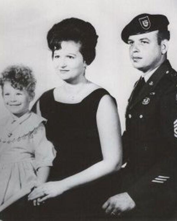 A man in a United States Army military dress uniform posed with a young woman and child. 