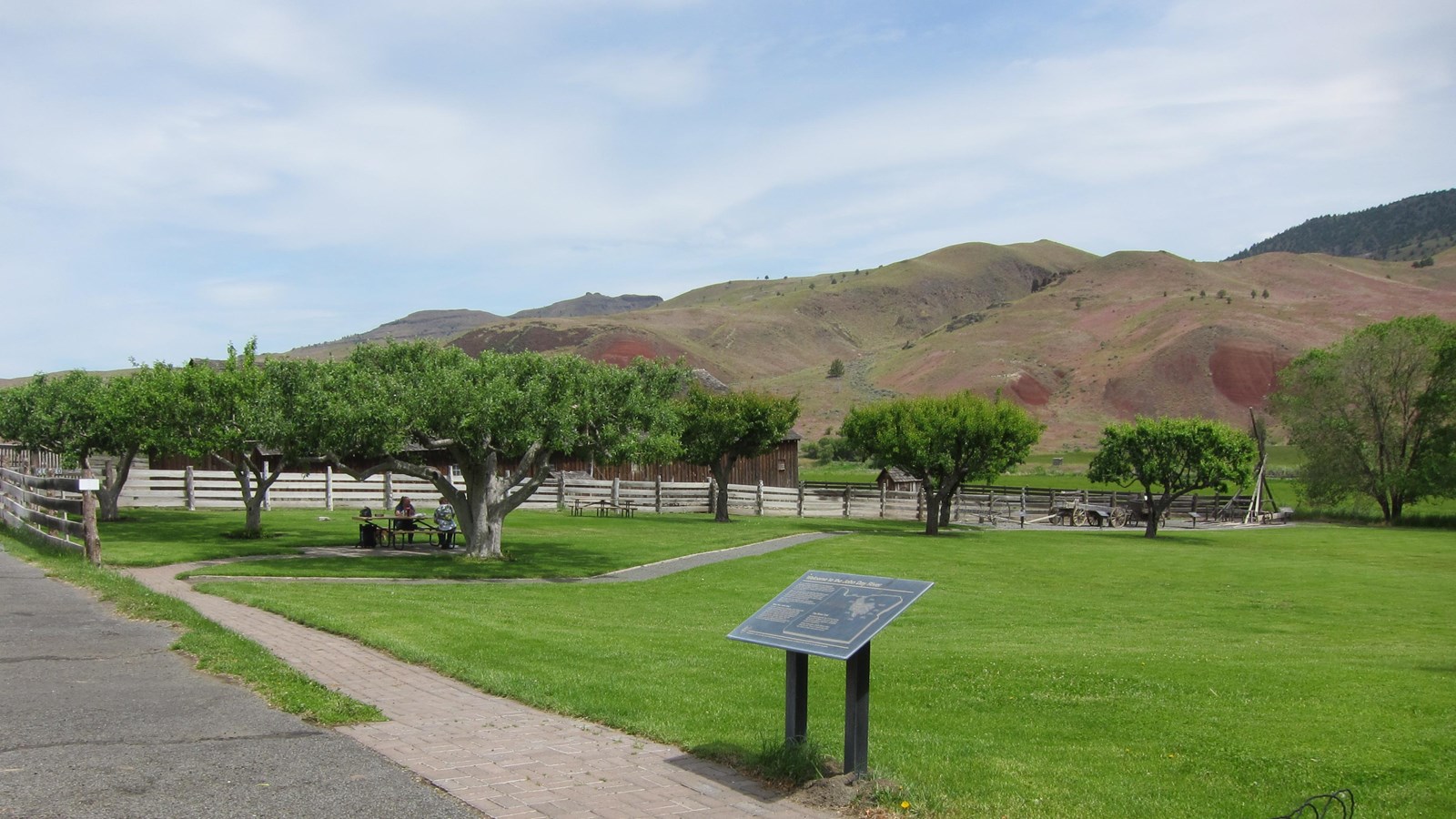 An interpretive wayside in view of a picnic table and open grassy space.