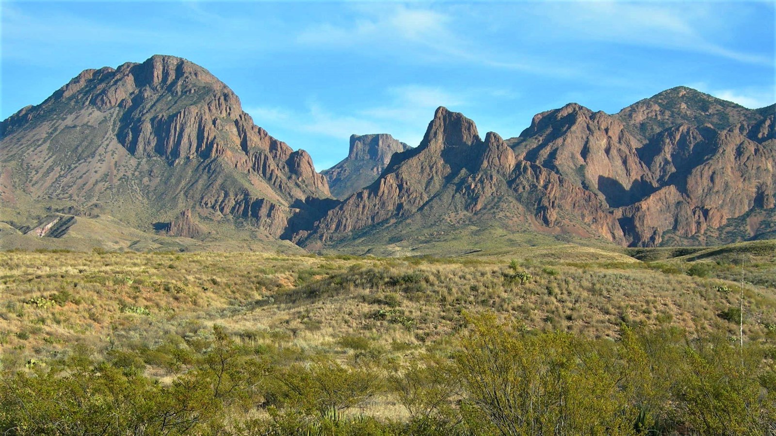 Rolling grasslands lead the eye up to the towering cliffs of the Chisos Mountains.