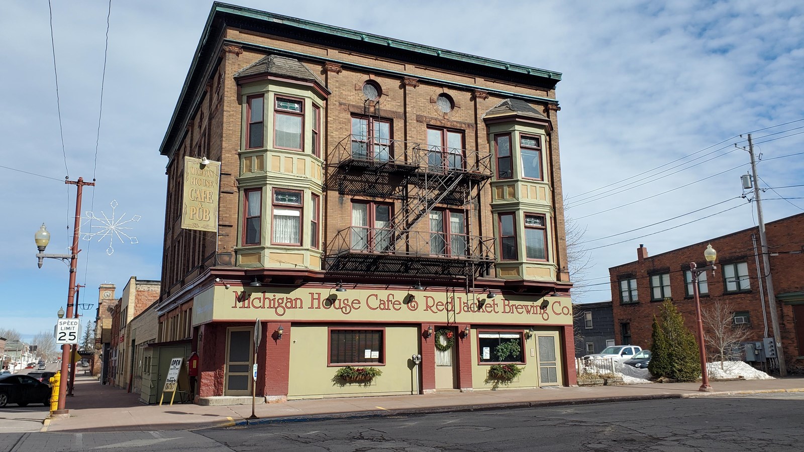 Three story yellow brick building with red sign: Michigan House Café and Red Jacket Brewing Company