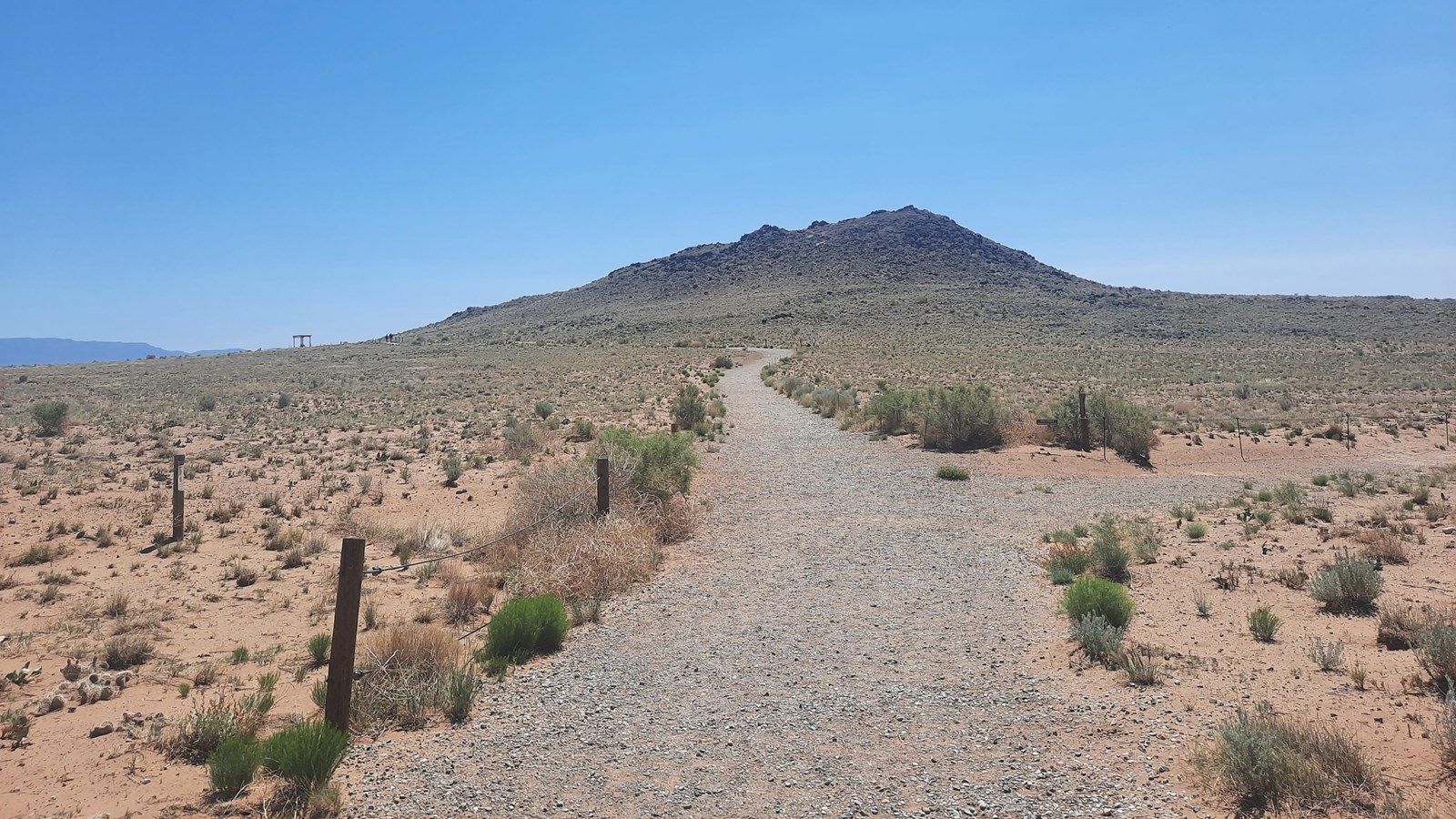 A path in a desert landscape heading towards a volcano.