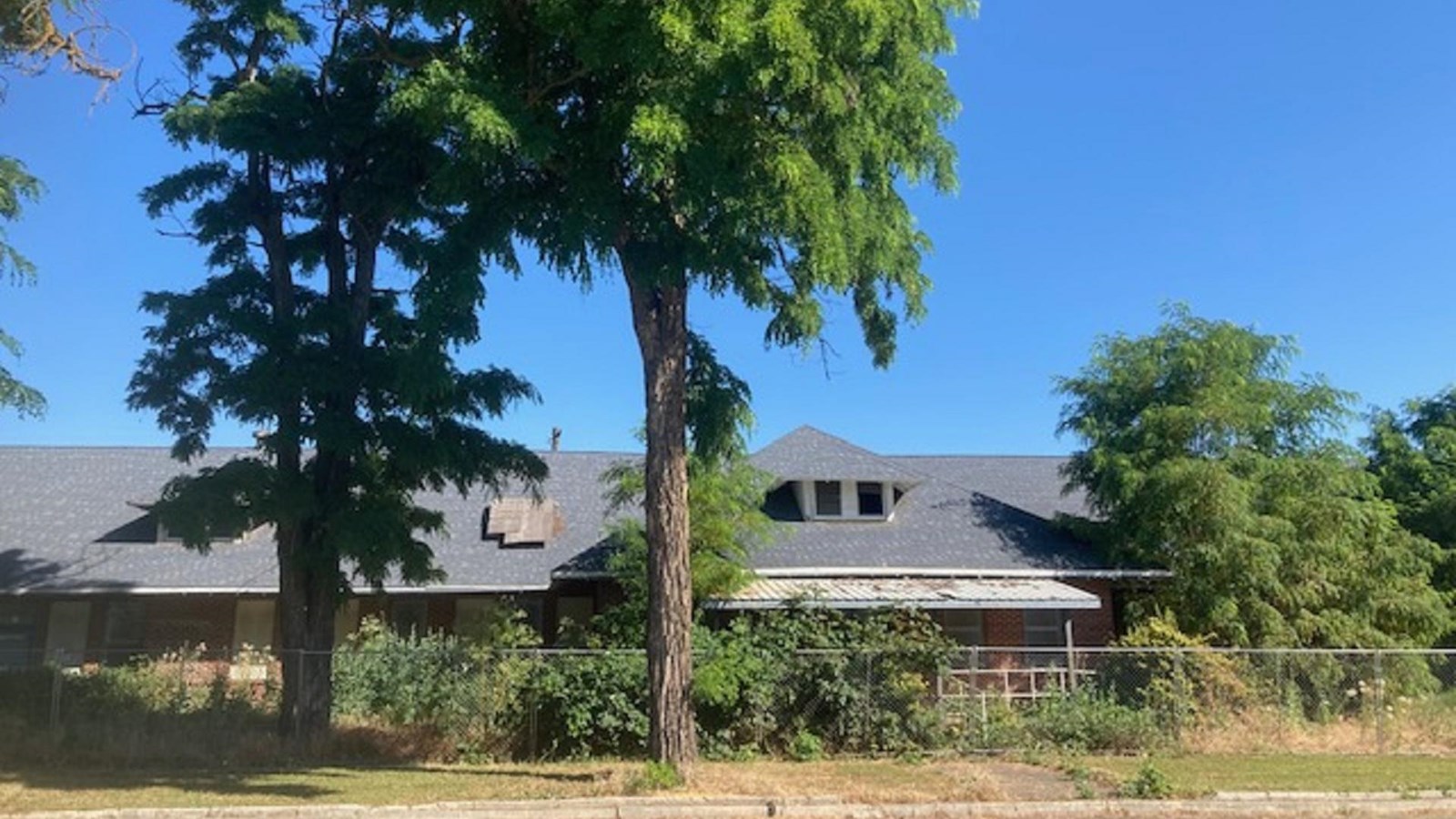 One story brick building surrounded by trees and shrubs