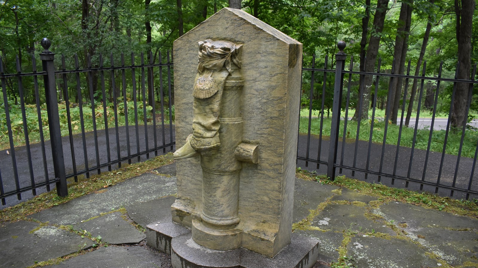 Monument depicting a boot draped over a cannon barrel. Monument is protected by an iron fence