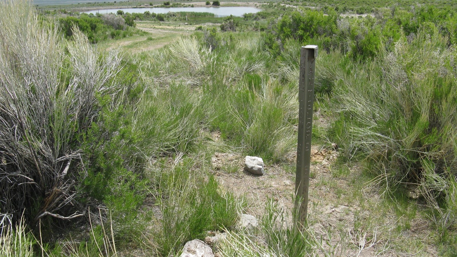 A silver steel post marks the site of Antelope Springs Station, surrounded by tall sagebrush.
