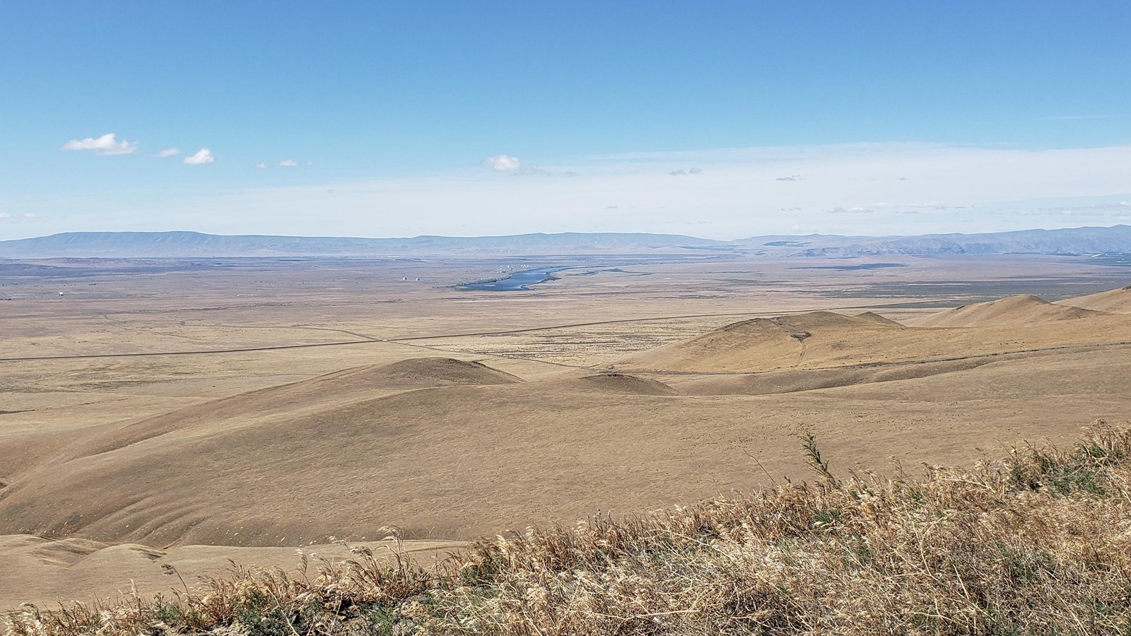 Color photograph of a mountaintop view of a large expanse of dry scrubland