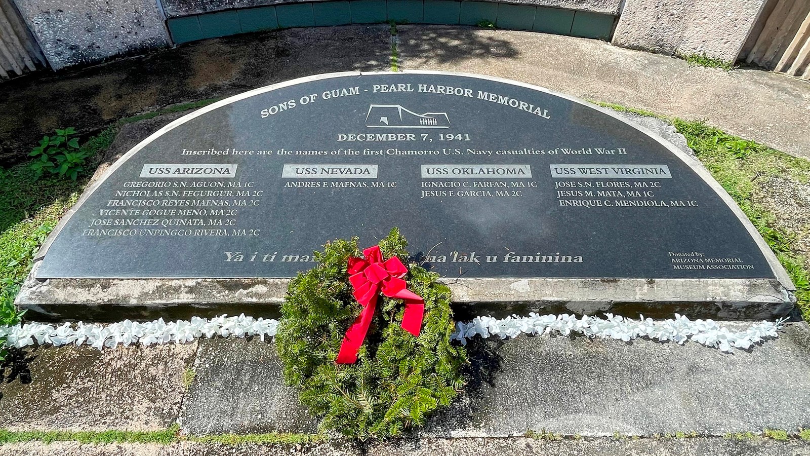 A semicircular plaque set into a concrete base. The plaque says “Sons of Guam Pearl Harbor Memorial