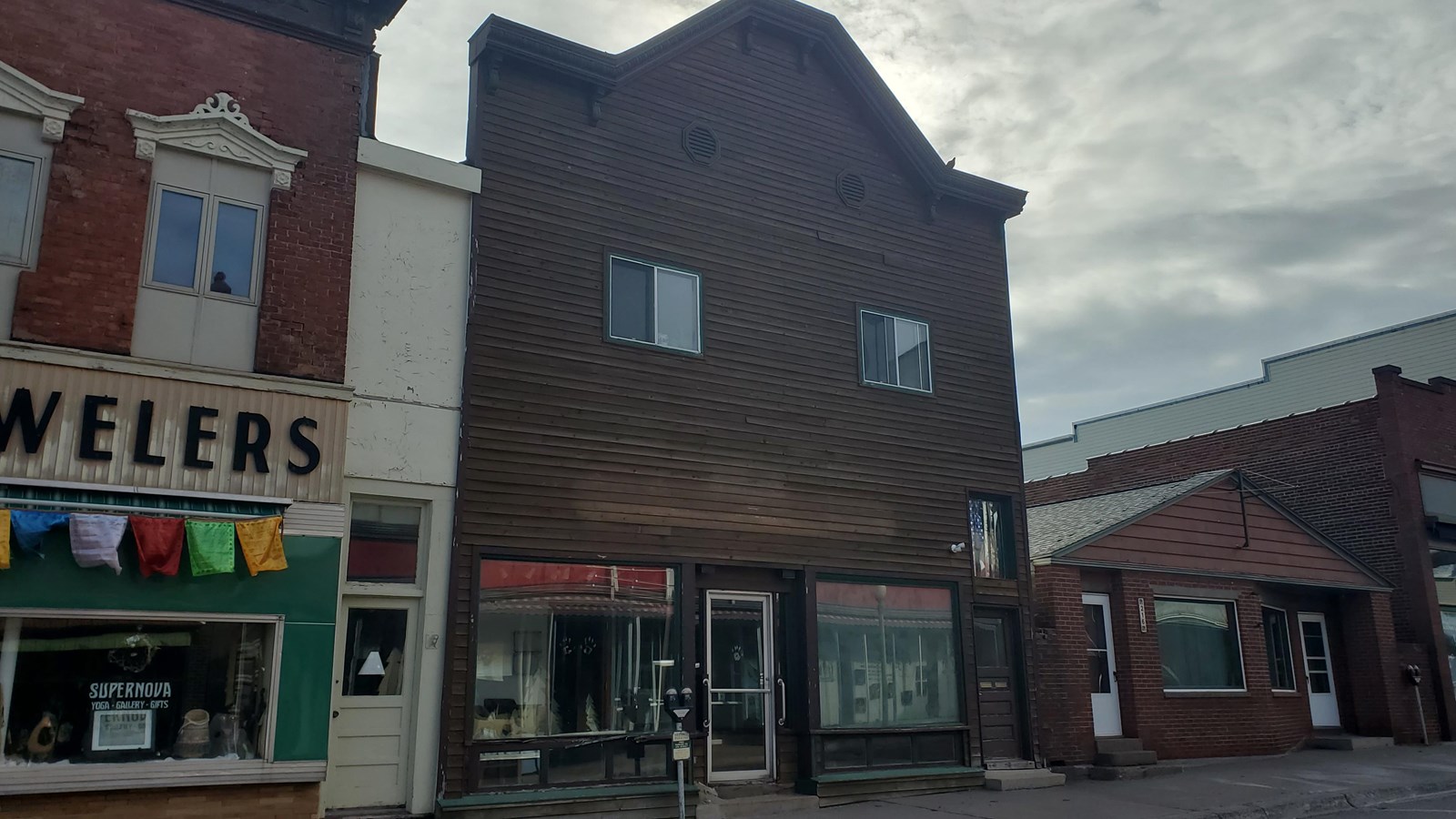 False fronted two-story building with dark brown wood siding.