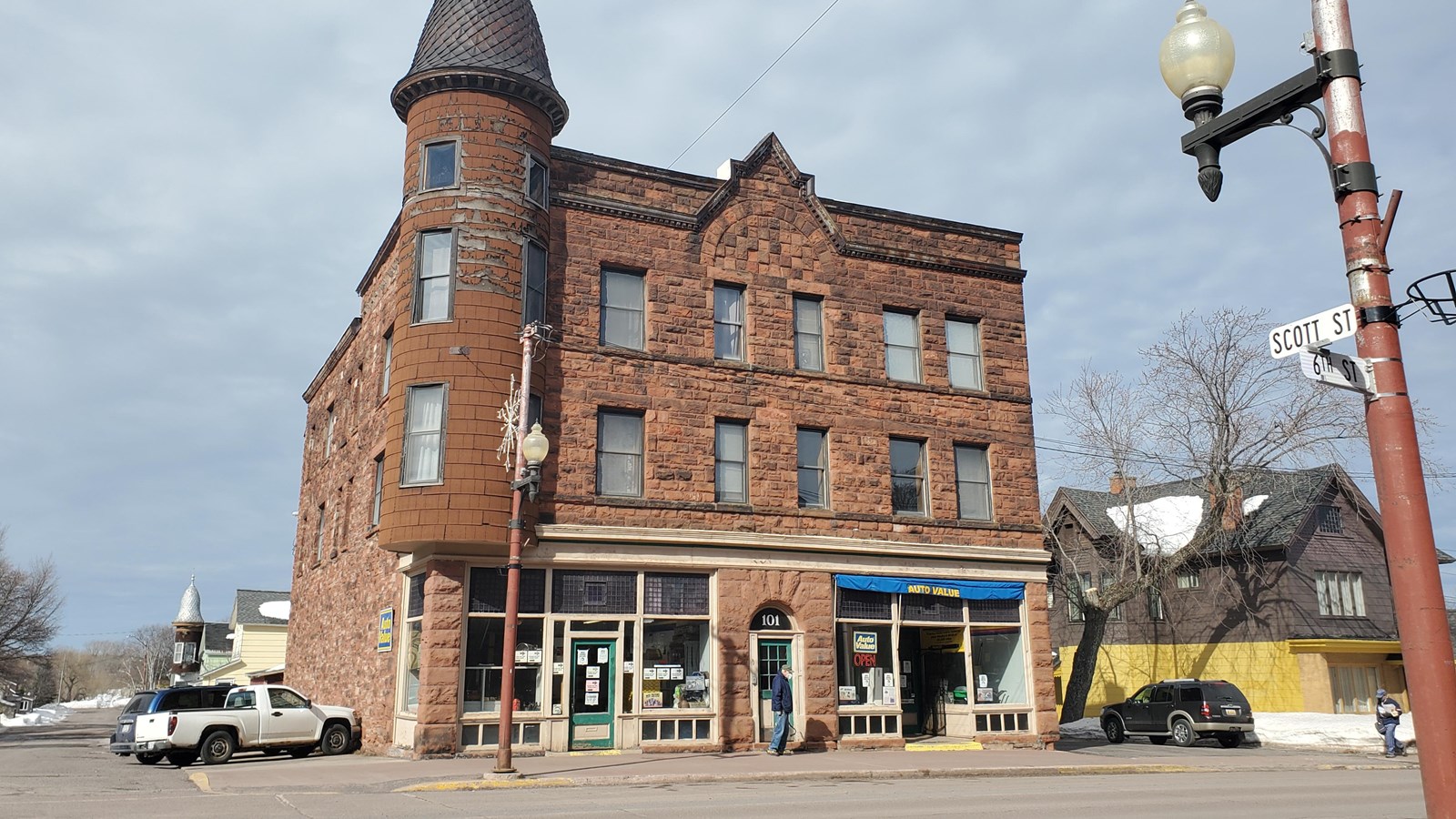 Three story red sandstone building with circular turret jutting out from the second and third floors