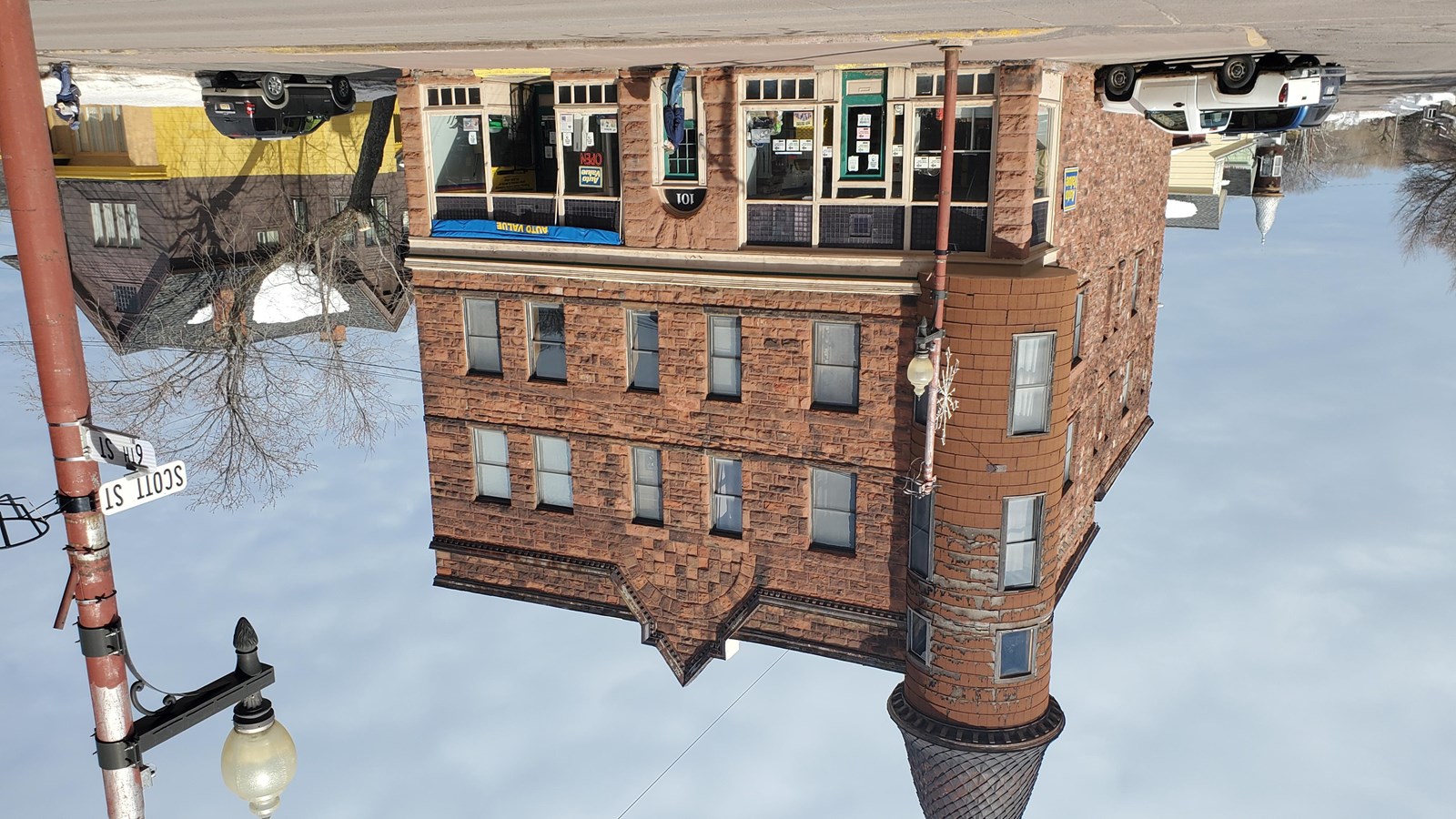 Three story red sandstone building with circular turret jutting out from the second and third floors