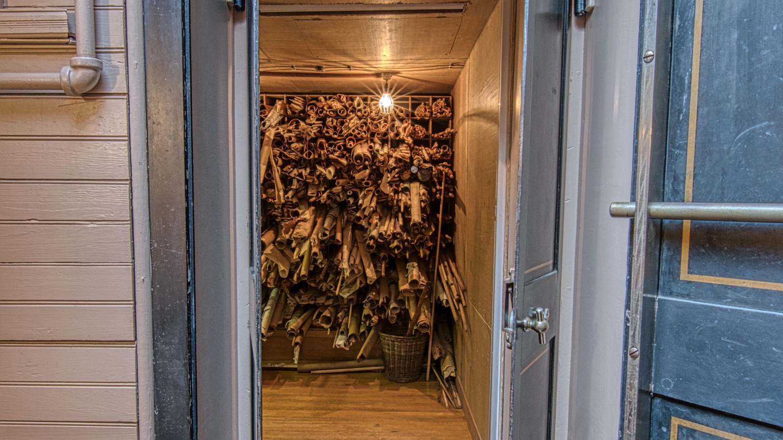 Metal doorway leading to group of rolled up pieces of paper stacked on each other.