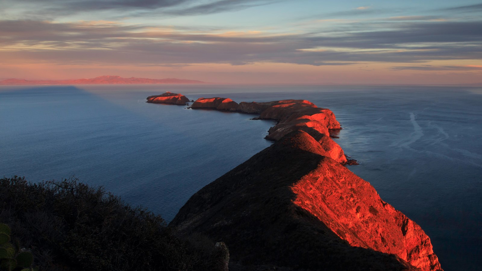 Aerial view of string of 3 islets at sunset.