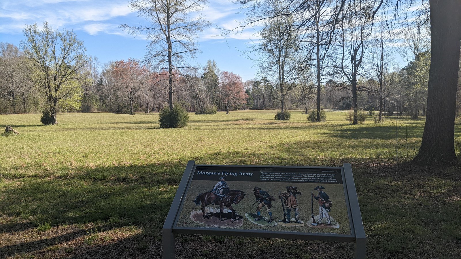 Morgan\'s Flying Army way side in front of a field with sparse trees and bushes.