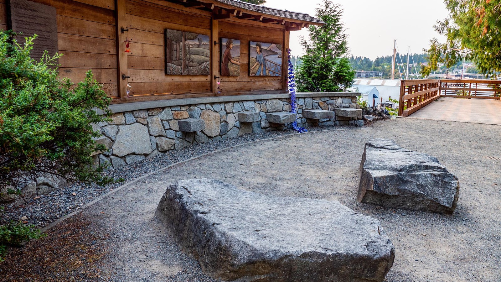 Large stones placed in front of curved wood wall memorial.