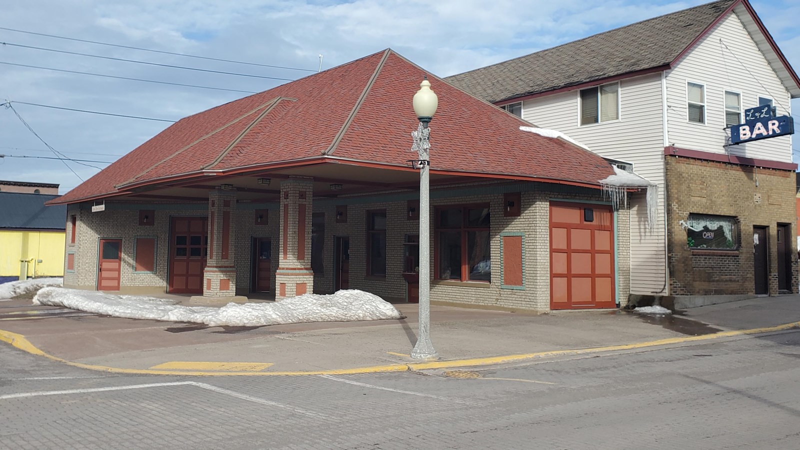 White brick gas station with red-trimmed windows and doors and a red-colored asphalt shingles.