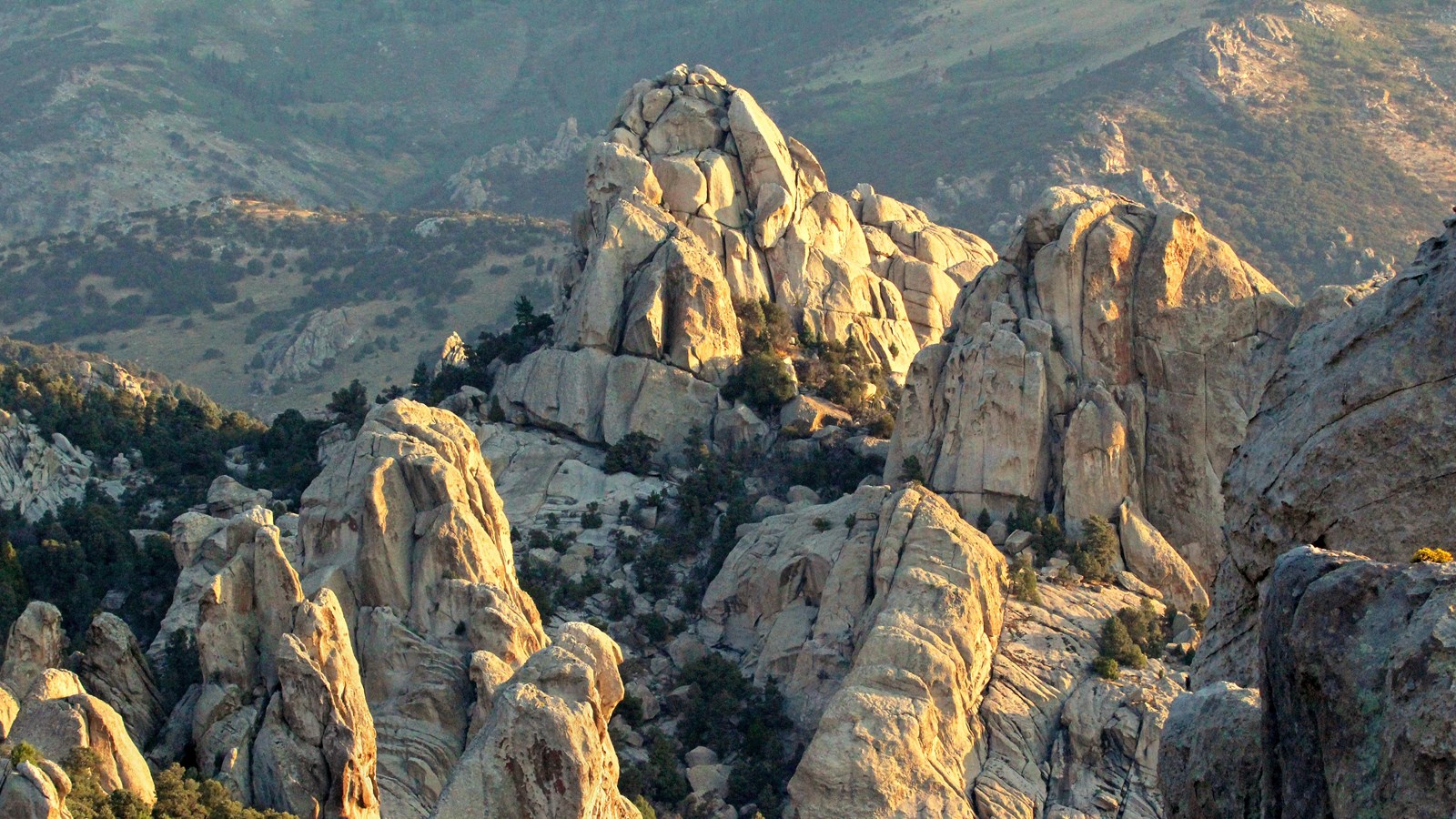 Craggy granite formations jut up in a mountainous landscape glowing in sunrise light.