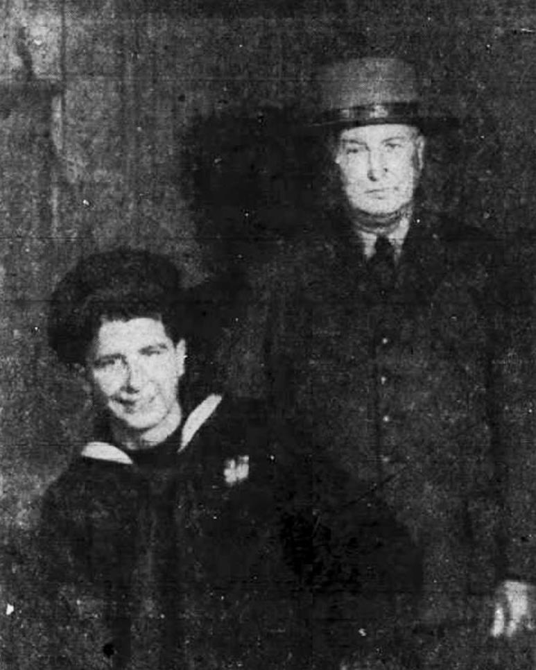 Photograph of an older man standing behind a seated young man. Both wear military uniforms.