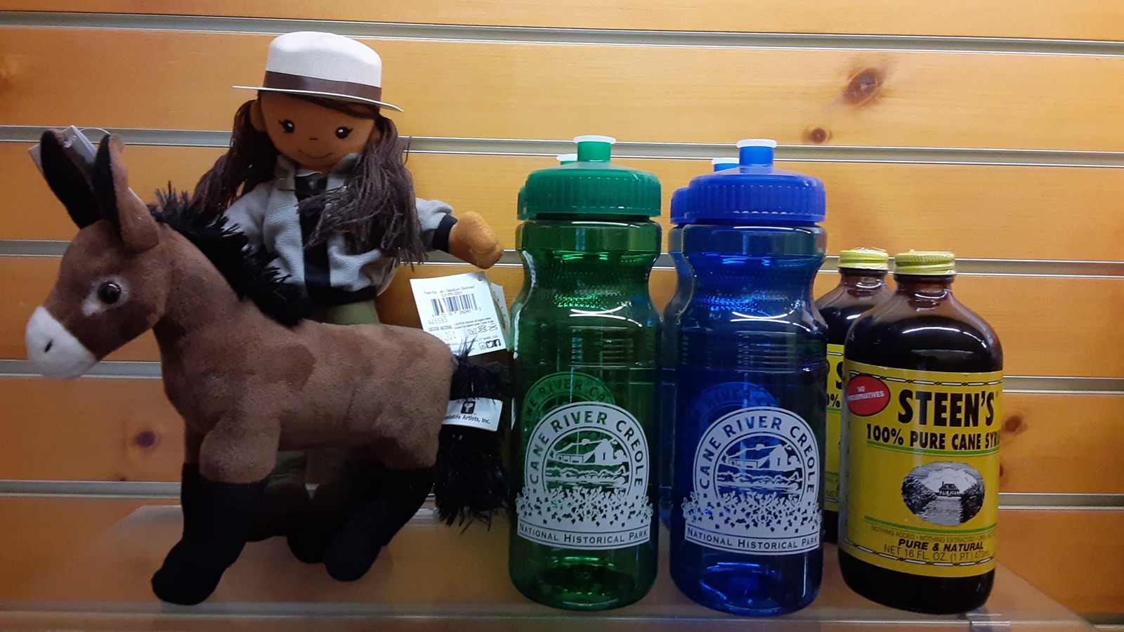 A display of items for purchase including toys, water bottles and cane syrup.