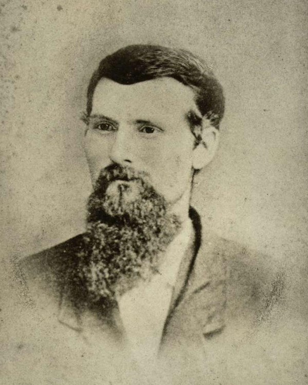 An 1879 portrait photo depicts a bearded man in a suit jacket.