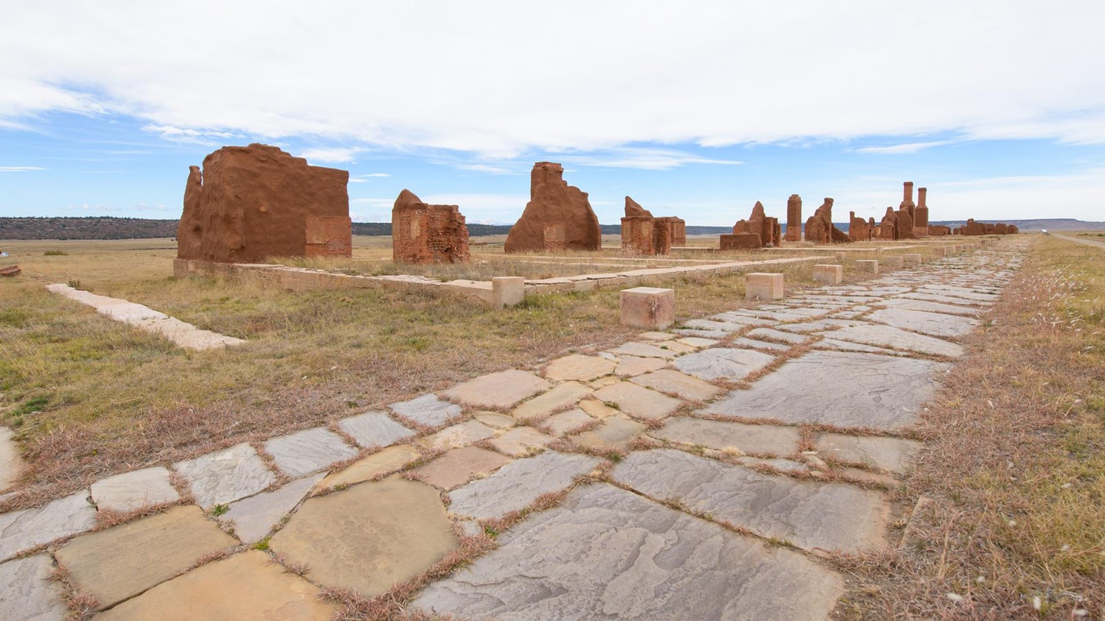 A stone path leads by the ruins of a wall of an old fort.