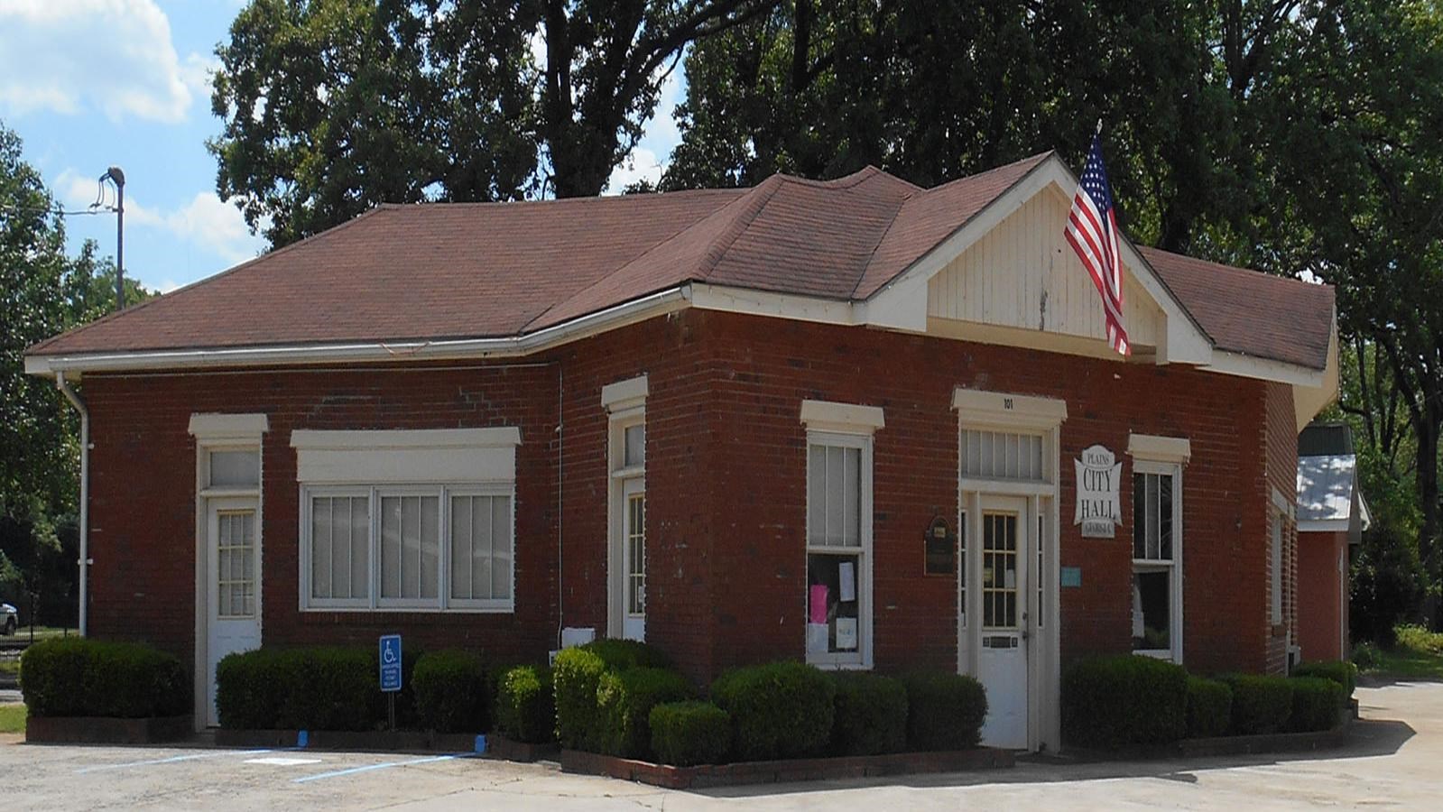 a red brick building with white trip that serves as Plains City Hall