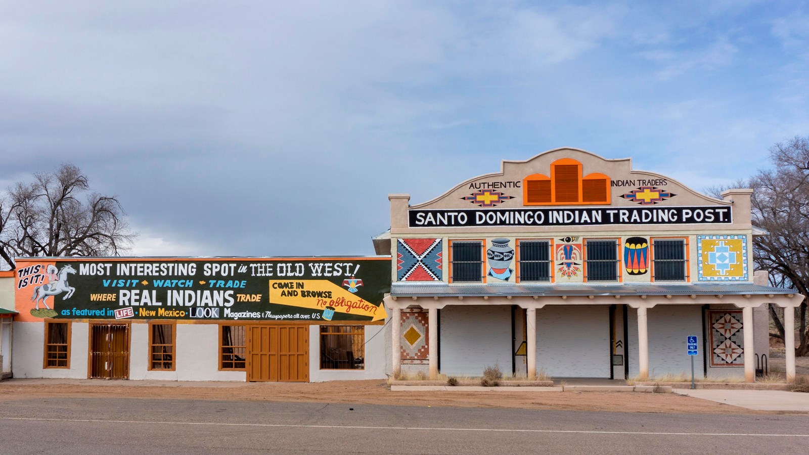 A two story white stucco building with a covered patio. A sign reads 