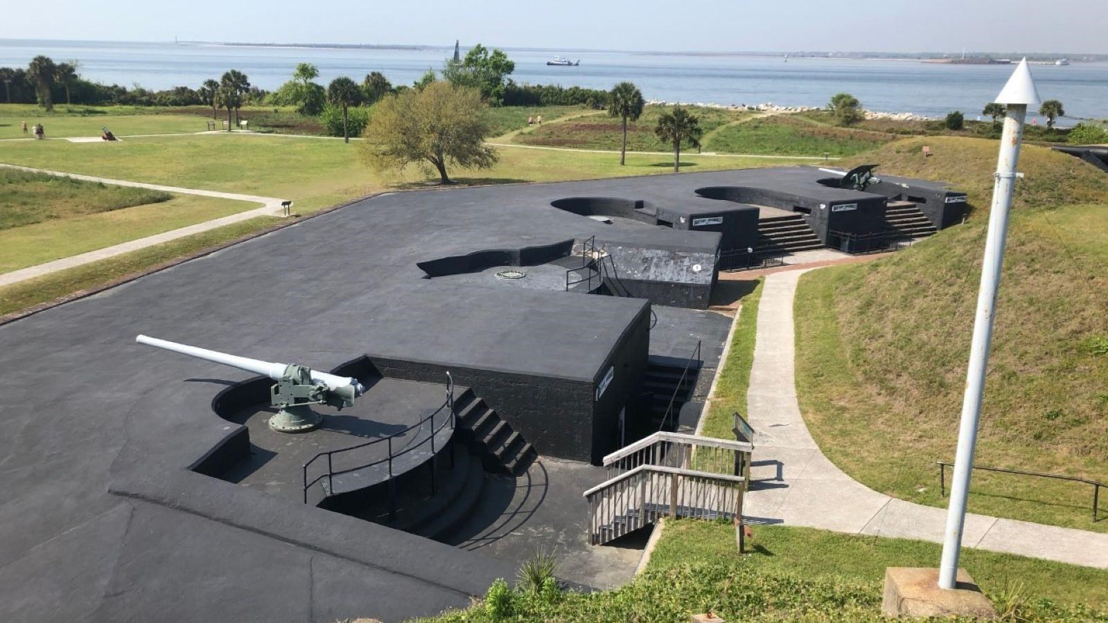 Two side by side concrete structures face Charleston Harbor. Nearest battery has a gun mounted.